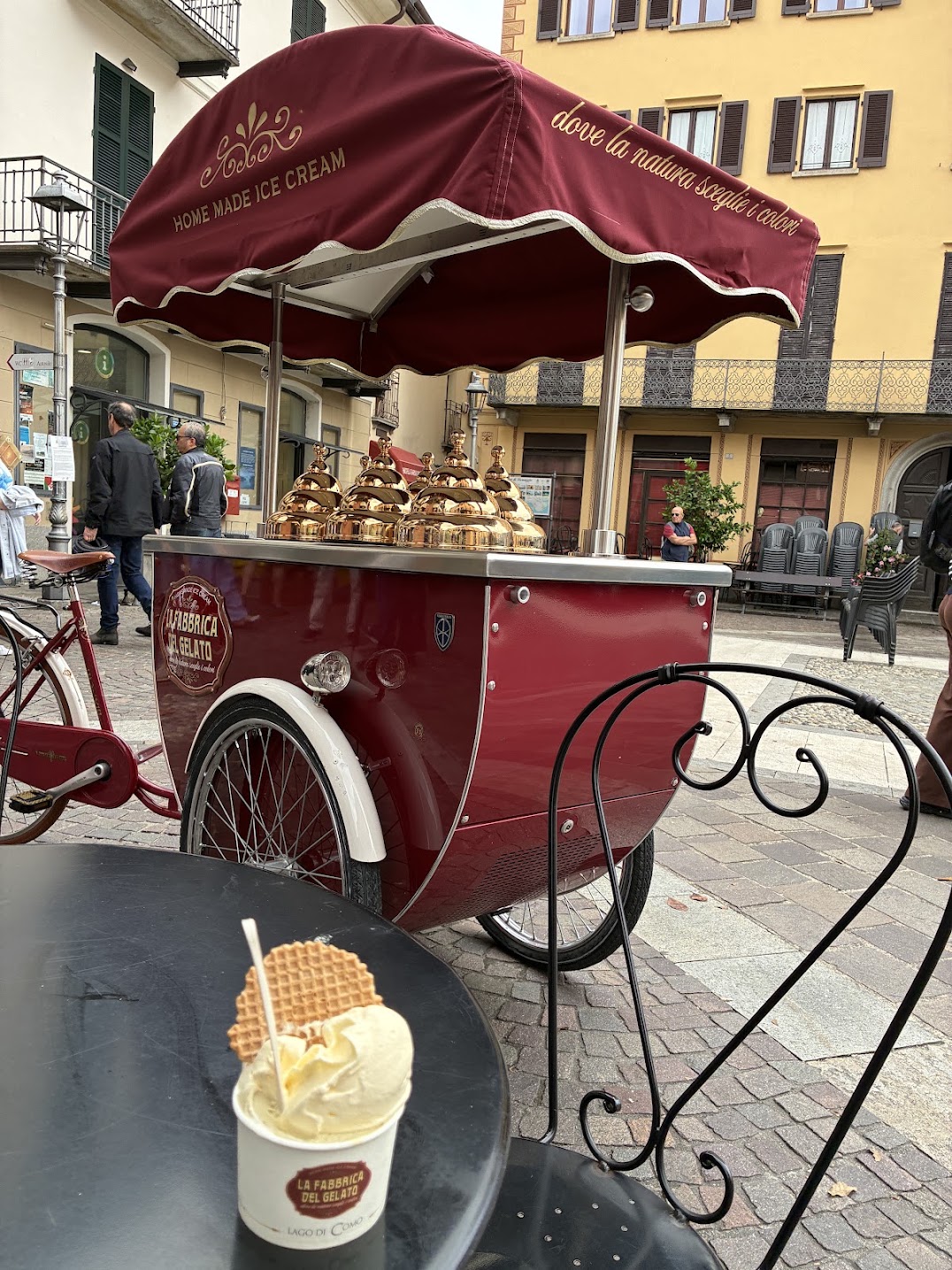 A traditional gelato cart with a red parasol standing in an Italian piazza