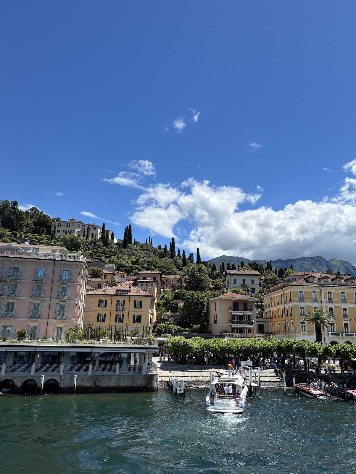 A bright summer afternoon on the Lake Como waterfront, with boats moored along the promenade