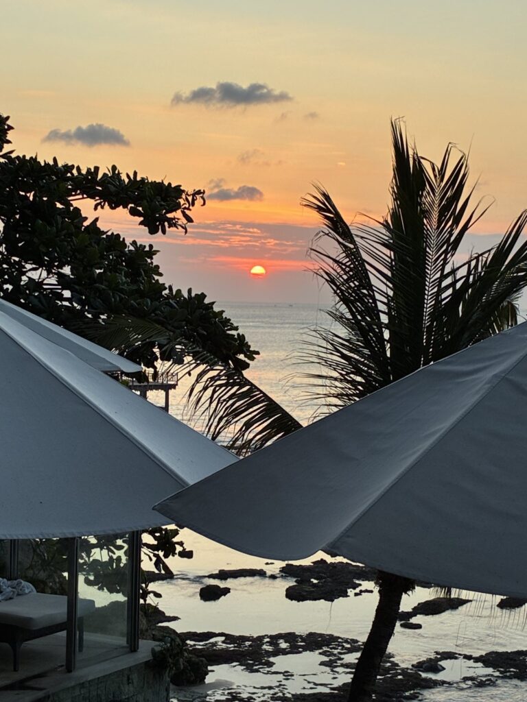 Sunset behind palm trees at AYANA Ocean Beach Pool